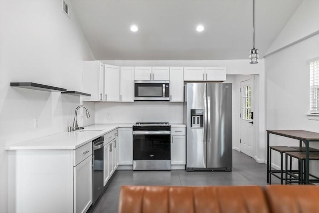 kitchen with lofted ceiling, a sink, white cabinetry, light countertops, and appliances with stainless steel finishes