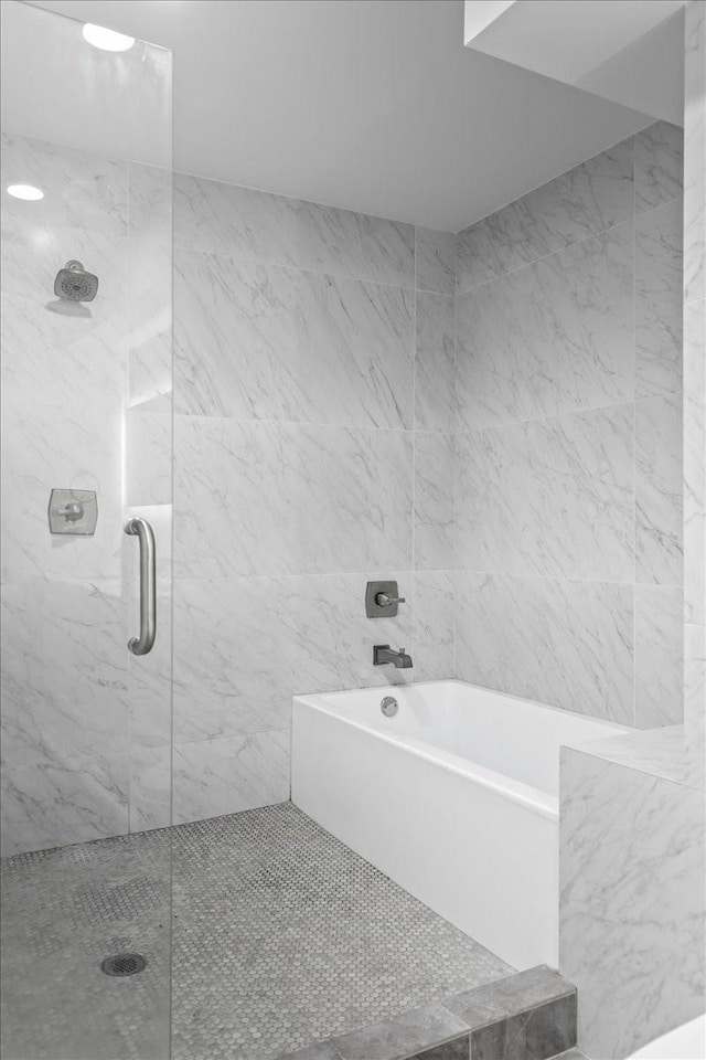 bathroom with a marble finish shower and a bath