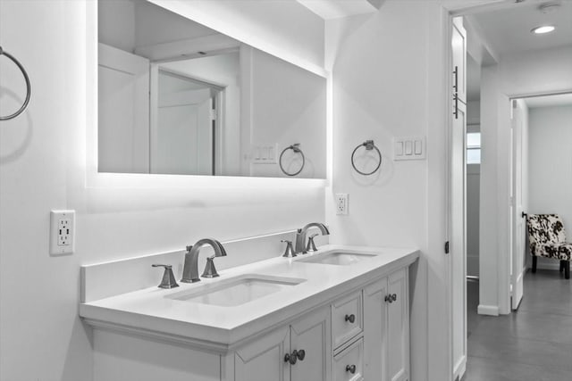 bathroom featuring double vanity, baseboards, and a sink