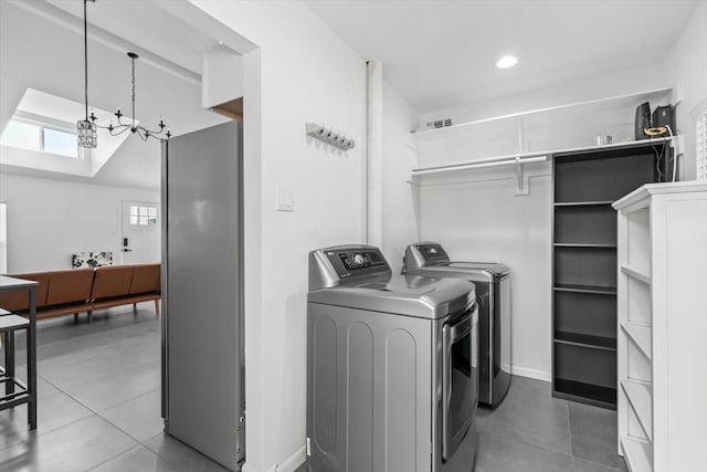 washroom featuring laundry area, washing machine and clothes dryer, tile patterned flooring, an inviting chandelier, and baseboards