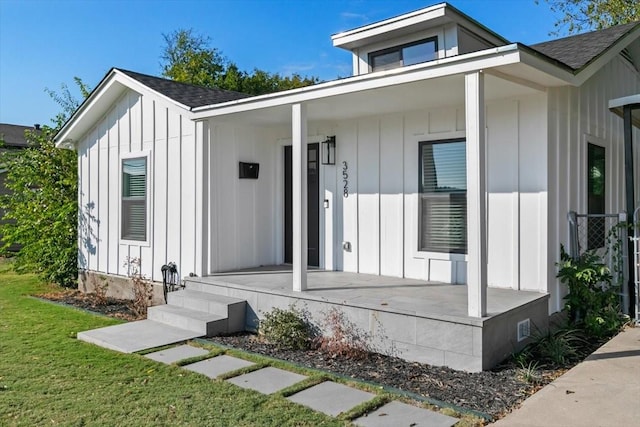 exterior space featuring a porch, a shingled roof, a front lawn, and board and batten siding