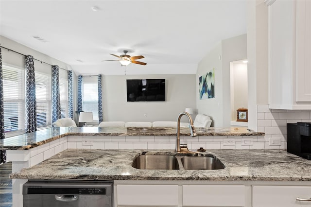 kitchen featuring dishwasher, light stone countertops, open floor plan, and a sink