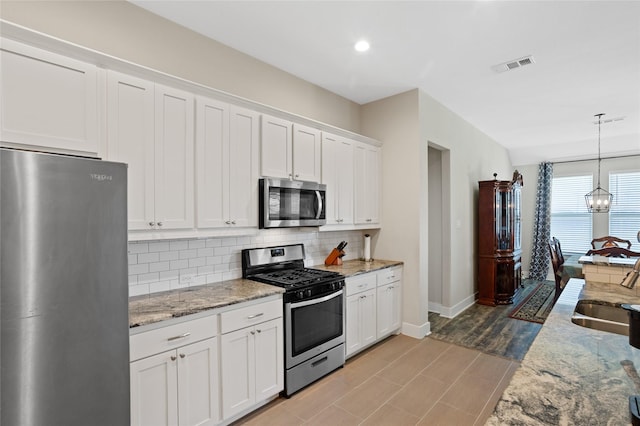 kitchen featuring baseboards, visible vents, a sink, tasteful backsplash, and appliances with stainless steel finishes