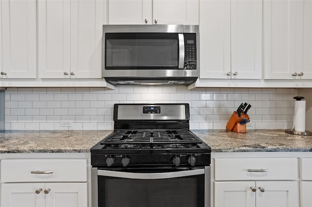 kitchen featuring light stone countertops, stainless steel appliances, tasteful backsplash, and white cabinets