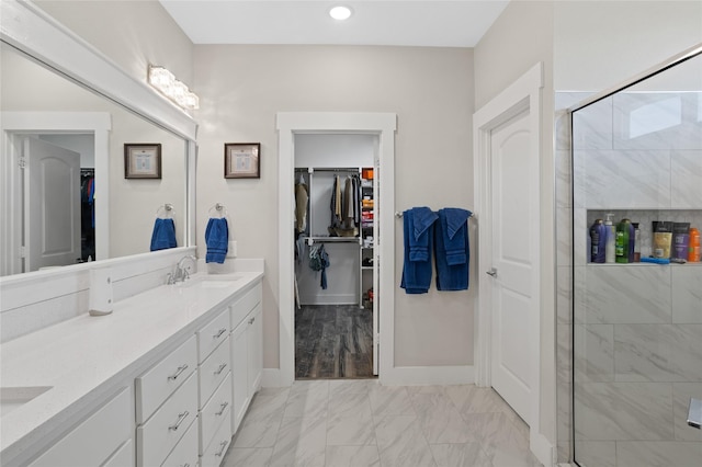 full bathroom featuring a sink, marble finish floor, a stall shower, a spacious closet, and double vanity