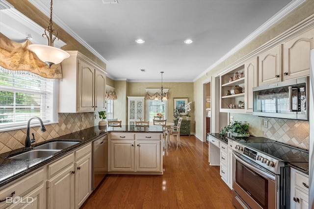 kitchen featuring recessed lighting, an inviting chandelier, a sink, a peninsula, and appliances with stainless steel finishes