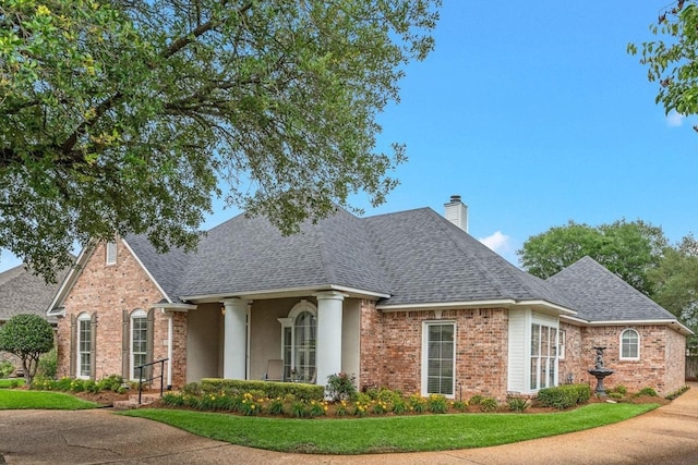 view of front of home featuring roof with shingles, a chimney, and brick siding