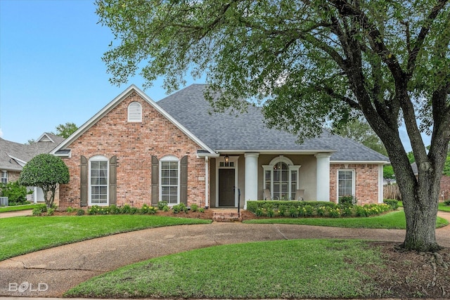 view of front of property featuring brick siding, roof with shingles, stucco siding, and a front yard