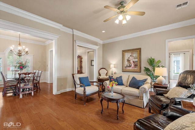 living room with crown molding, visible vents, light wood-style flooring, and ceiling fan with notable chandelier