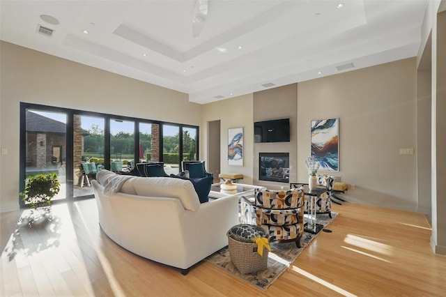 25 White Rock Trl, Lucas, TX 75002 - living room with a raised ceiling, a glass covered fireplace, light wood-type flooring, and a high ceiling