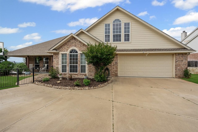 view of front of house with brick siding, driveway, fence, and roof with shingles
