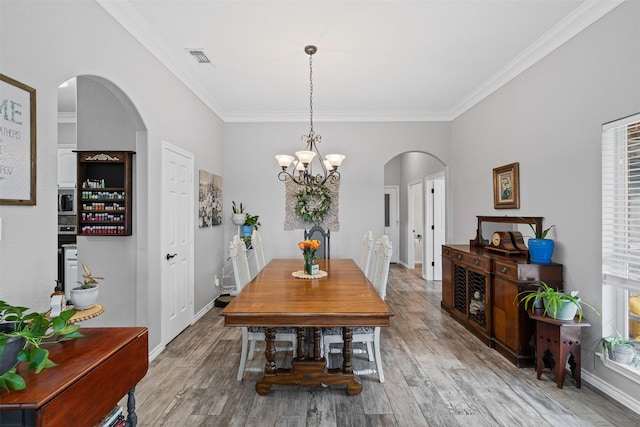 dining room featuring ornamental molding, wood finished floors, and arched walkways