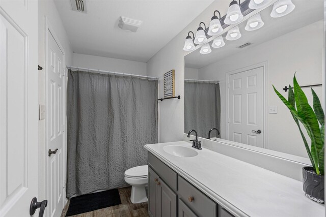 full bathroom featuring toilet, visible vents, wood finished floors, and vanity