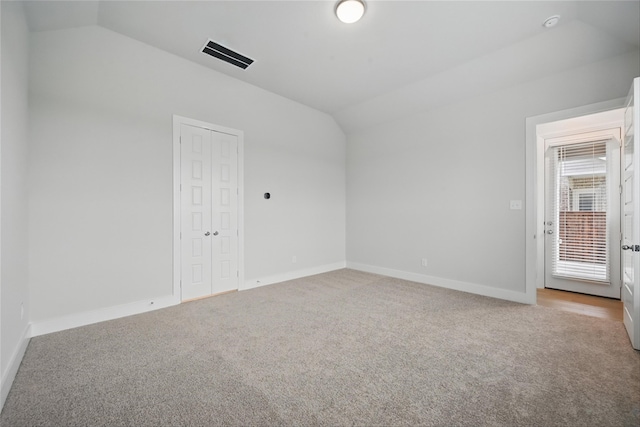 spare room featuring visible vents, baseboards, lofted ceiling, and carpet floors