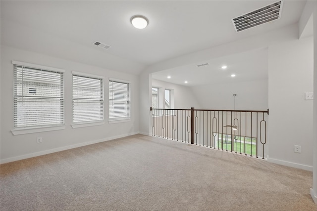 carpeted spare room with lofted ceiling, baseboards, visible vents, and recessed lighting