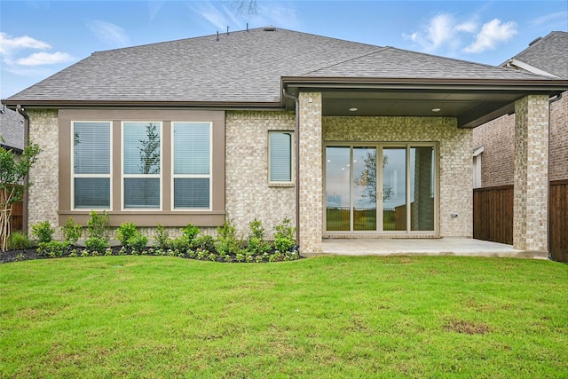 rear view of property featuring a shingled roof, a patio, and a yard