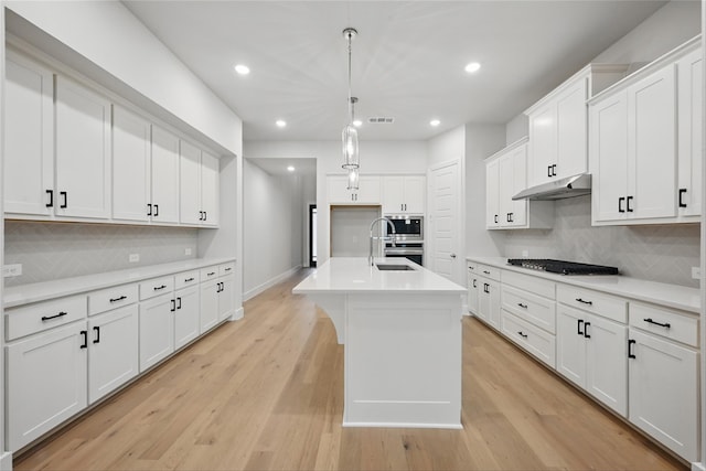 kitchen featuring gas cooktop, decorative backsplash, visible vents, and stainless steel microwave