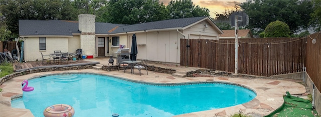 pool at dusk with a patio, fence, and a fenced in pool