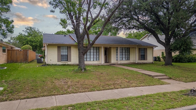 ranch-style home with cooling unit, fence, a porch, a front yard, and brick siding