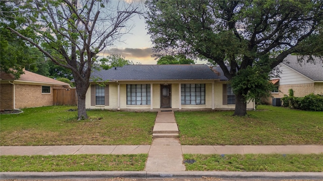 ranch-style house featuring fence, cooling unit, brick siding, and a lawn