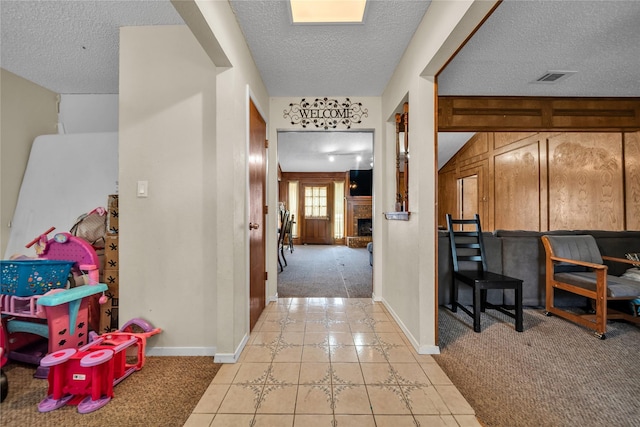 hallway featuring a textured ceiling, baseboards, and light colored carpet