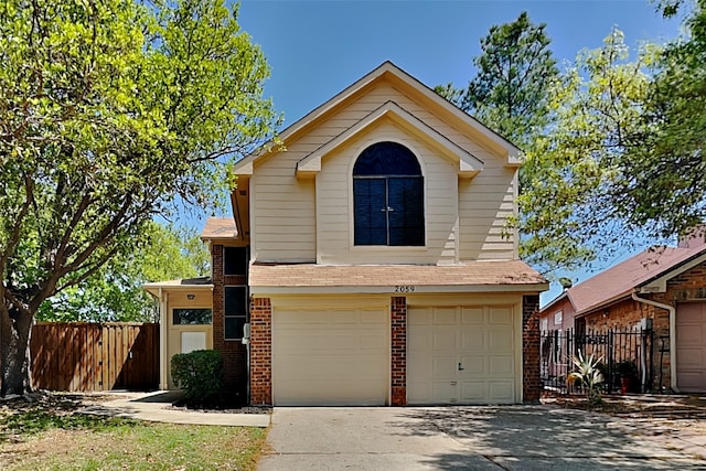 traditional-style home featuring fence, concrete driveway, a garage, and brick siding