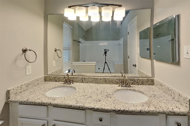 bathroom featuring double vanity, a walk in shower, and a sink