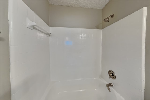 bathroom with a textured ceiling and washtub / shower combination