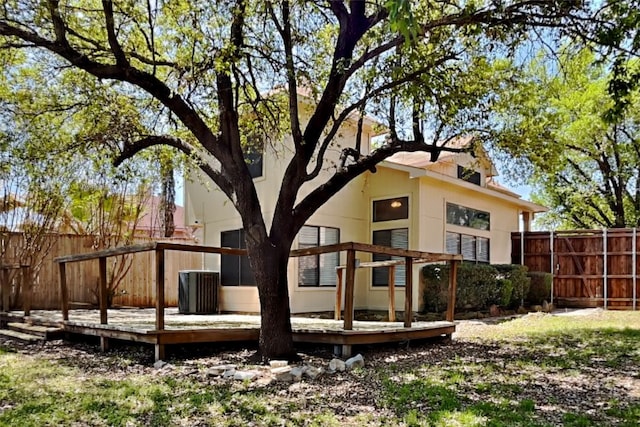 rear view of house featuring central air condition unit, a deck, stucco siding, and fence