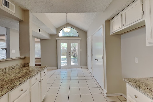 entryway with a textured ceiling, visible vents, light tile patterned flooring, and vaulted ceiling