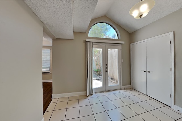 entryway featuring baseboards, french doors, light tile patterned floors, and vaulted ceiling