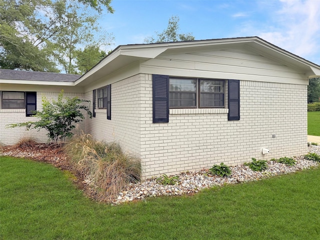view of side of property featuring a yard and brick siding