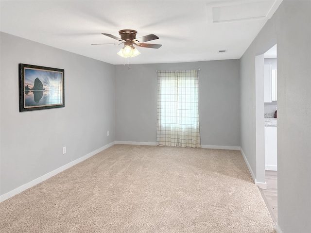 spare room with attic access, light carpet, baseboards, and a ceiling fan