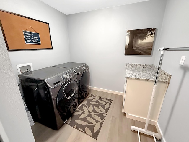 clothes washing area featuring baseboards, washing machine and dryer, laundry area, and light wood-type flooring
