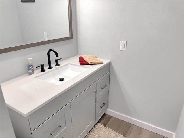 bathroom with vanity, baseboards, and wood finished floors