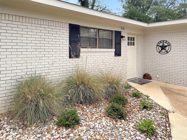 view of exterior entry featuring brick siding
