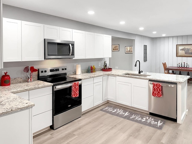 kitchen featuring a sink, a peninsula, stainless steel appliances, and white cabinets