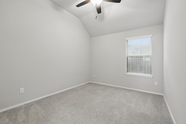 carpeted empty room featuring a ceiling fan, baseboards, and vaulted ceiling