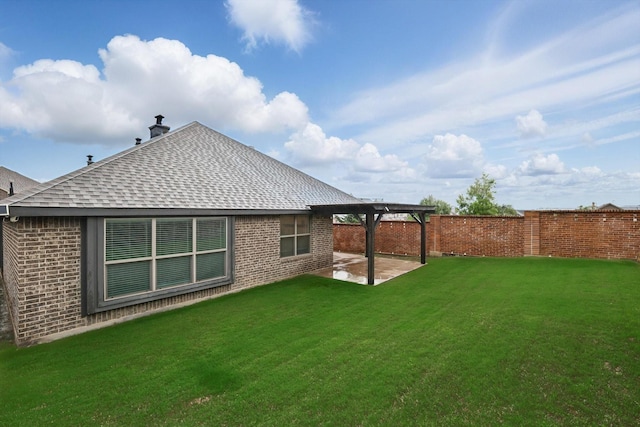 rear view of house featuring a lawn, brick siding, fence, a patio area, and a shingled roof