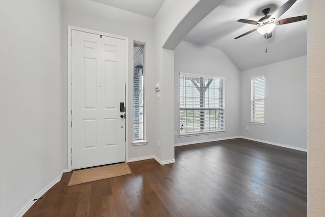 foyer entrance with a ceiling fan, baseboards, vaulted ceiling, arched walkways, and wood finished floors