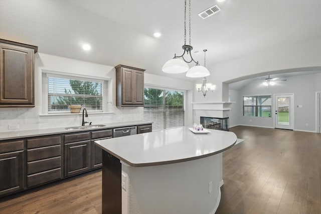 kitchen featuring a multi sided fireplace, visible vents, dark brown cabinets, and a sink