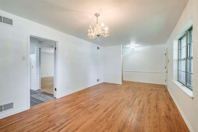 437 Summit Dr, Richardson, TX 75081 - spare room featuring light wood-style flooring, a chandelier, and baseboards