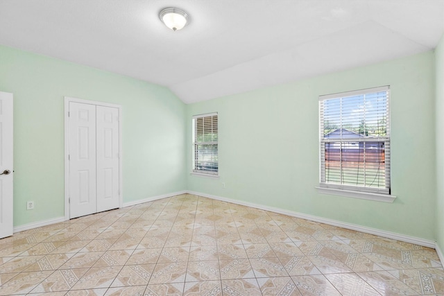 908 E Belknap St, Ennis, TX 75119 - unfurnished bedroom featuring vaulted ceiling, baseboards, light tile patterned floors, and a closet