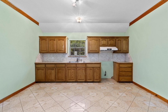 908 E Belknap St, Ennis, TX 75119 - kitchen featuring under cabinet range hood, a sink, decorative backsplash, brown cabinets, and ornamental molding