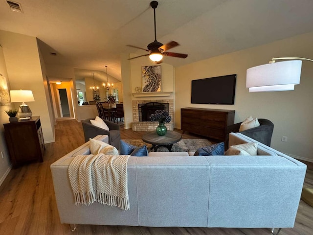 living area featuring baseboards, visible vents, wood finished floors, and ceiling fan with notable chandelier