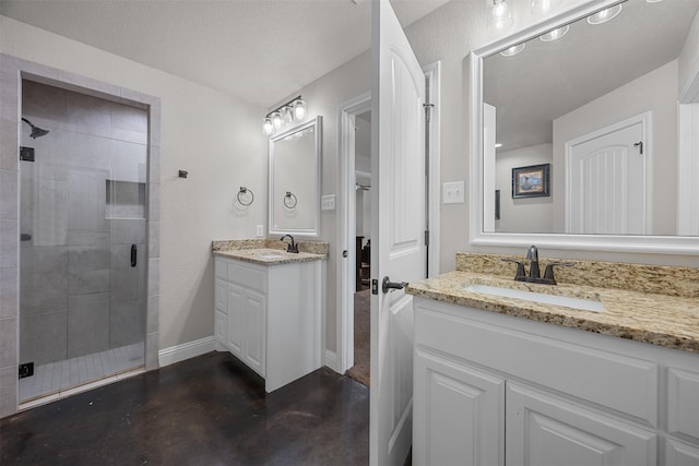 bathroom with finished concrete floors, a shower stall, two vanities, and a sink