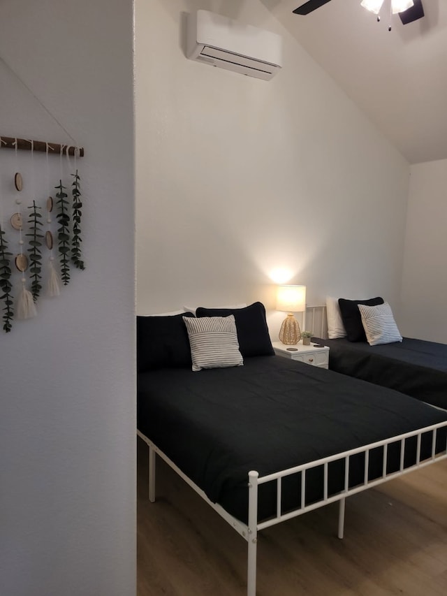 bedroom featuring a ceiling fan, vaulted ceiling, a wall mounted air conditioner, and wood finished floors