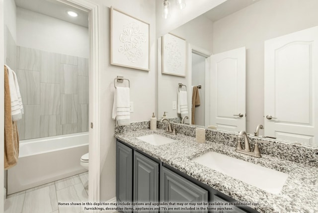 bathroom with toilet, marble finish floor, double vanity, and a sink