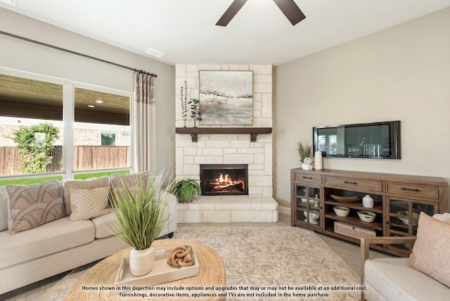 living area featuring a stone fireplace, visible vents, wood finished floors, and ceiling fan