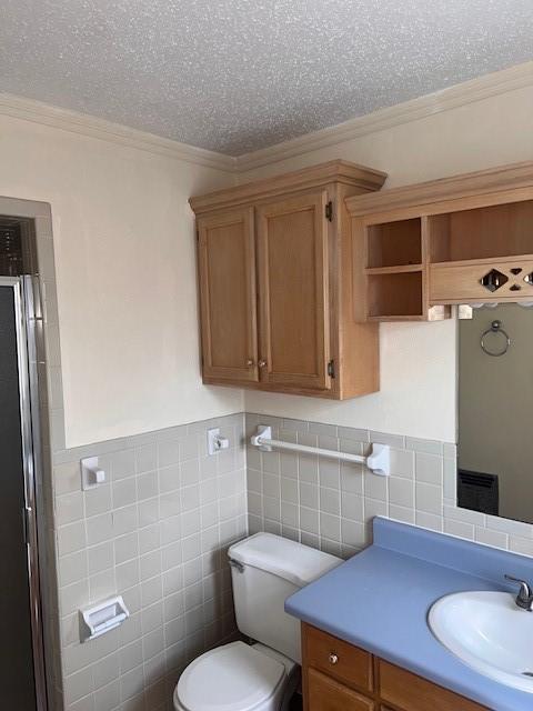 full bathroom featuring tile walls, a textured ceiling, toilet, ornamental molding, and vanity